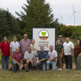 Group of Beck's Hybrids and Growing Hope Globally staff and volunteers around a Growing Hope Globally Sign