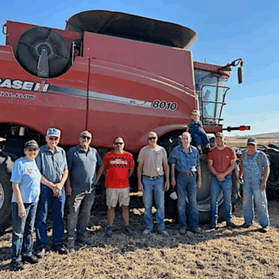 Fields of Faith Volunteers stand with Combine in Background