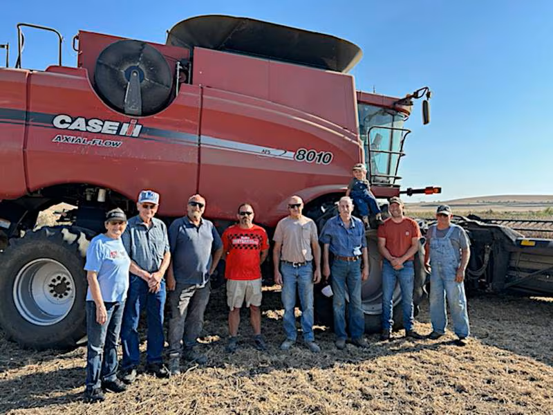 Fields of Faith Volunteers stand with Combine in Background