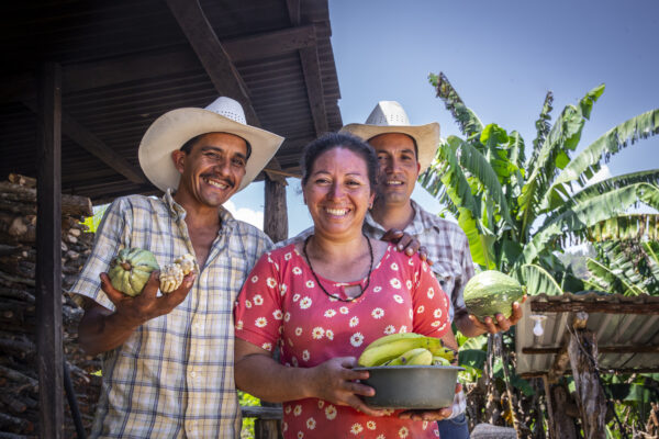 Don Pedro and his wife and brother holding some of the food they've produced